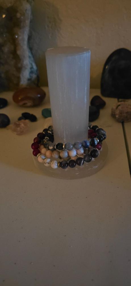 Customer photo: selenite harmonizer with seven bracelets stacked at its base